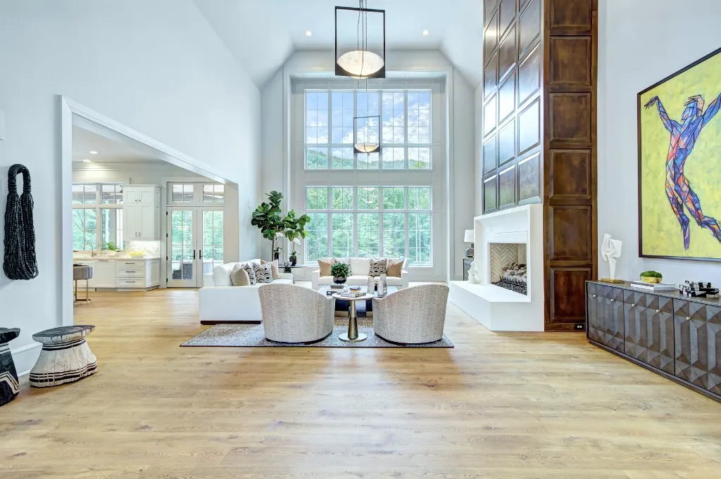 Mtn Lake — vaulted living room with forest views and wood-paneled fireplace